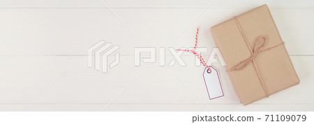 Gift box with kraft paper and tag or label on wooden table in Christmas day or holiday. Gift box with kraft paper and tag or label on wooden table in Christmas day or holiday. 71109079
