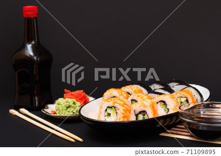 Uramaki California. Sushi rolls, bottle and bowl with soy sauce. 71109895