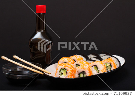 Uramaki California. Sushi rolls, bottle and bowl with soy sauce. 71109927