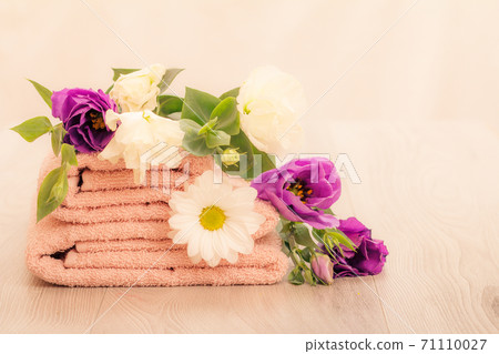 Stack of soft terry towels with flowers on wooden boards 71110027