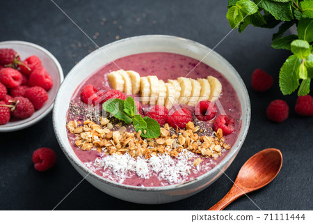 Pink smoothie bowl with raspberry, banana, granola and coconut 71111444