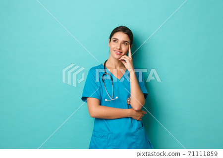 Coronavirus, pandemic and social distancing concept. Image of pleased and thoughtful female doctor in scrubs, looking at upper left corner and thinking, smiling intrigued Coronavirus, pandemic and social distancing concept. Image of pleased and thoughtful female doctor in scrubs, looking at upper left corner and thinking, smiling intrigued 71111859