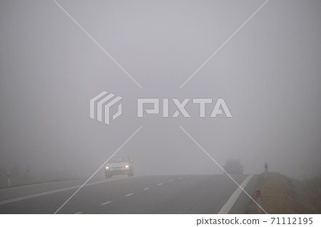 Car on the road in the fog. Autumn landscape - dangerous road traffic in winter season. 71112195