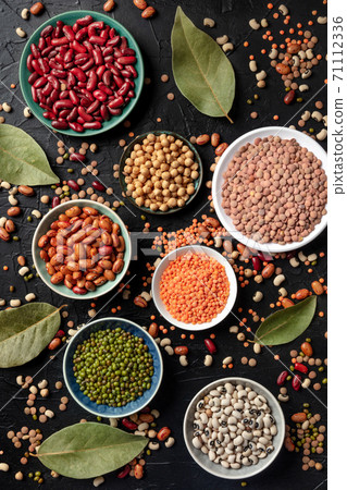 Various legumes, shot from the top on a dark background. Lentils, soybeans, chickpeas, red kidney beans, black-eyed peas and other pulses 71112336