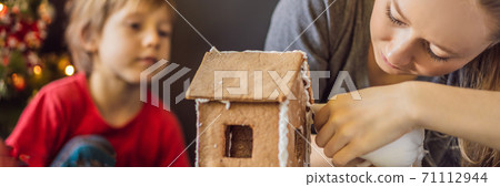 Young mother and kid making gingerbread house on Christmas eve BANNER, LONG FORMAT Young mother and kid making gingerbread house on Christmas eve BANNER, LONG FORMAT 71112944