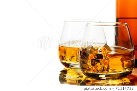 Glass of whisky and ice on a white background Glass of whisky and ice on a white background 71114732