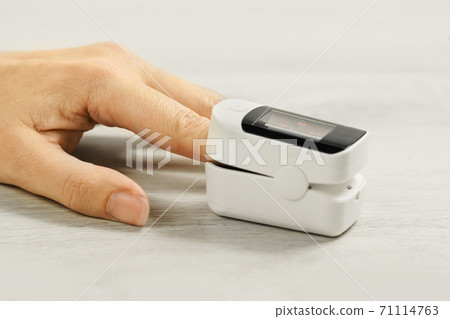 Female hand with pulse oximeter on table 71114763