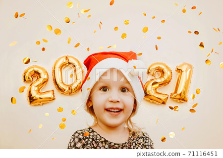 Little girl in Santa cap smiles against the background of golden numbers 2021 Little girl in Santa cap smiles against the background of golden numbers 2021 71116451