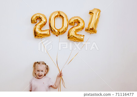 Little girl holding golden balloons with golden numbers 2021 on wall background Little girl holding golden balloons with golden numbers 2021 on wall background 71116477