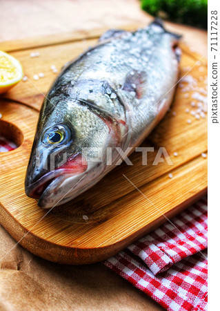 Raw fish on a chopping Board close-up with a slice of lemon.Texture or background Raw fish on a chopping Board close-up with a slice of lemon.Texture or background 71117228