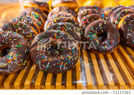 Delicious frosted chocolate donut displayed on shelf in pastry shop 71117261