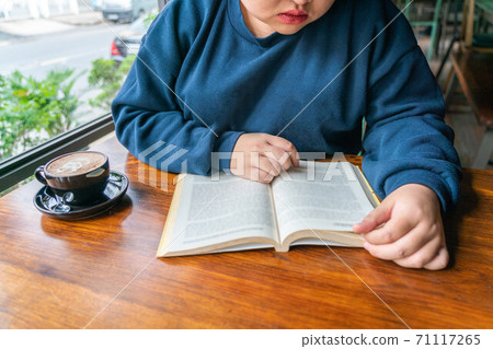 Young girl drinking coffee and reading book Young girl drinking coffee and reading book 71117265