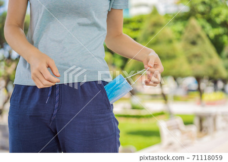 Improper wearing of mask concept. Woman wants to wear an old, crumpled used mask 71118059