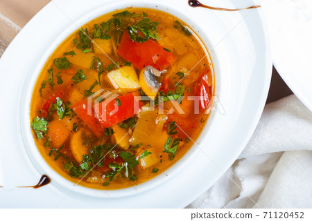 Traditional vegetable soup broth in a white plate on a table in a restaurant. Traditional vegetable soup broth in a white plate on a table in a restaurant. 71120452