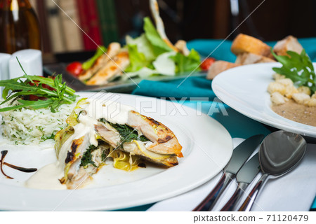 Fillet of white fish sea bass, cod stuffed with greens and rice on the table in the restaurant. 71120479