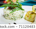 Fillet of white fish sea bass, cod stuffed with greens and rice on the table in the restaurant. 71120483