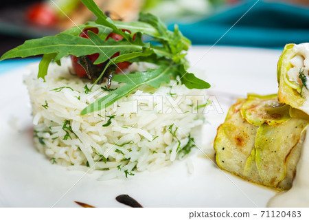 Fillet of white fish sea bass, cod stuffed with greens and rice on the table in the restaurant. Fillet of white fish sea bass, cod stuffed with greens and rice on the table in the restaurant. 71120483