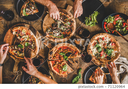 People eating various kinds of pizza and drinking People eating various kinds of pizza and drinking 71120964