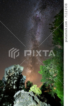 High boulder illuminated under the milky way with tree shadow 71121438