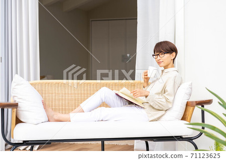 Woman reading on an outdoor sofa 71123625