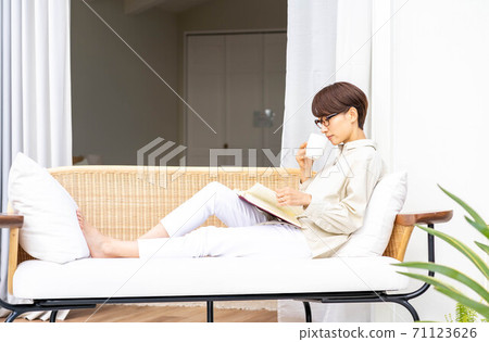 Woman reading on an outdoor sofa 71123626