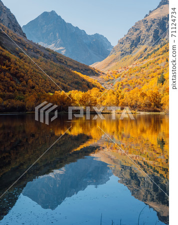 Mountain lake with transparent water, reflection and colorful autumnal trees. Mountains and lake Mountain lake with transparent water, reflection and colorful autumnal trees. Mountains and lake 71124734