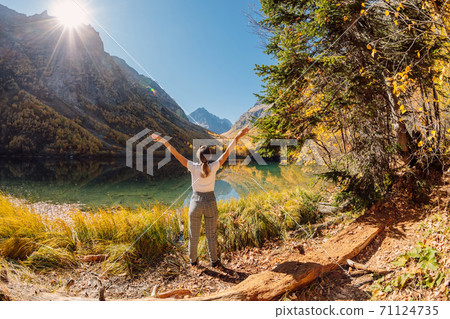 Woman hiker relax at crystal lake in the autumnal mountains. Mountain lake and traveller Woman hiker relax at crystal lake in the autumnal mountains. Mountain lake and traveller 71124735