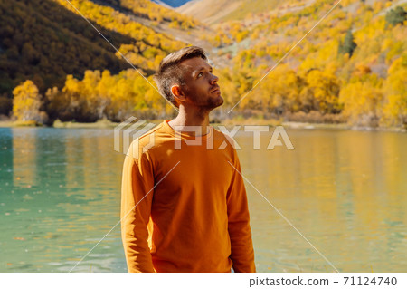 Happy man at the crystal lake in autumnal mountains. Mountain lake and hiker traveller Happy man at the crystal lake in autumnal mountains. Mountain lake and hiker traveller 71124740