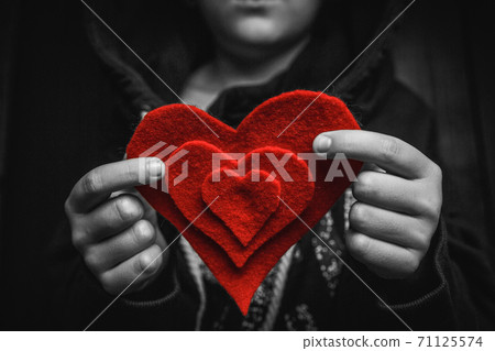 child with red heart on dark background. 71125574