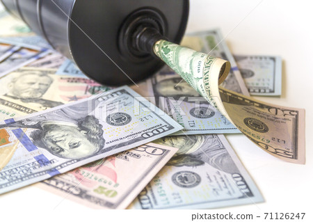 Barrel of oil on a background, american dollars background. Falling trend of barrel price decrease of earning and global economics . Selective focus. Barrel of oil on a background, american dollars background. Falling trend of barrel price decrease of earning and global economics . Selective focus. 71126247