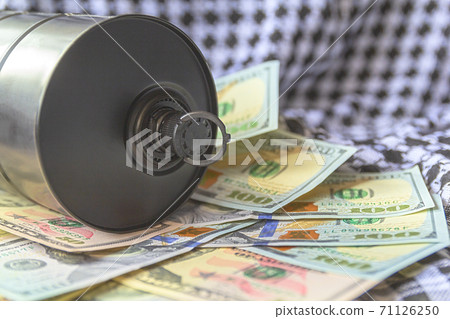 Barrel of oil on a background, american dollars and arabian background. Falling trend of barrel price decrease of earning and global economics . Selective focus. Barrel of oil on a background, american dollars and arabian background. Falling trend of barrel price decrease of earning and global economics . Selective focus. 71126250