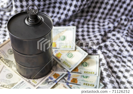 Barrel of oil on a background, american dollars and arabian background. Falling trend of barrel price decrease of earning and global economics . Selective focus. Barrel of oil on a background, american dollars and arabian background. Falling trend of barrel price decrease of earning and global economics . Selective focus. 71126252