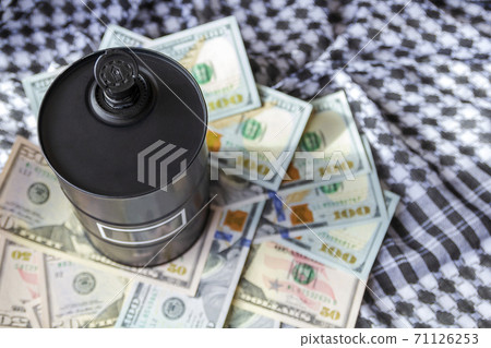 Barrel of oil on a background, american dollars and arabian background. Word on barrel is Oil. Falling trend of barrel price decrease of earning and global economics . Selective focus. 71126253