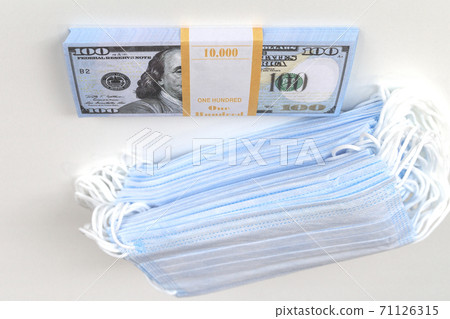 Blue medical masks, and american money.High price of masks and demand during quarantine in United States, Europe and global pandemic. Pile of anti virus surgical face masks and money. Concept. Blue medical masks, and american money.High price of masks and demand during quarantine in United States, Europe and global pandemic. Pile of anti virus surgical face masks and money. Concept. 71126315