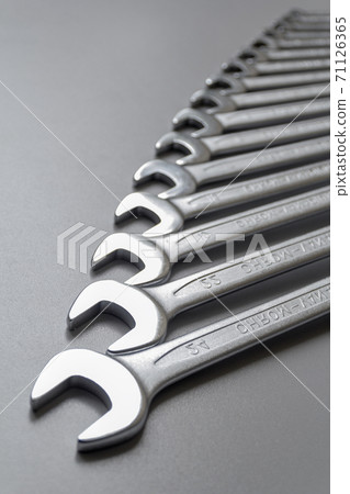 Spanners. Many wrenches. Grey background. Set of wrenches in different sizes on grey background. Vertical format. 71126365