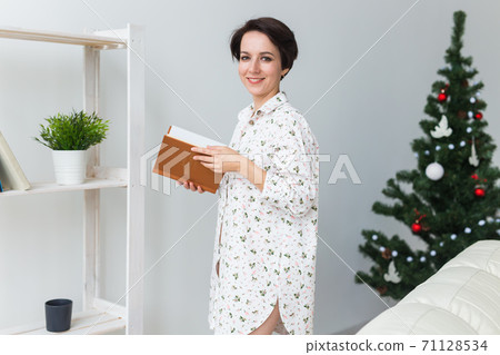 Beautiful young woman decorating a Christmas tree. Holidays and celebrations concept. 71128534