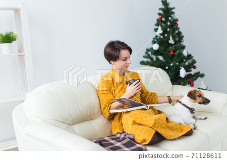 Christmas, holidays and people concept - happy young woman reading book at home. 71128611