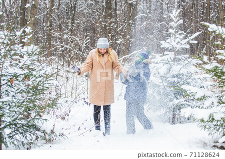 Fun and season concept - Happy mother and son having fun and playing with snow in winter forest Fun and season concept - Happy mother and son having fun and playing with snow in winter forest 71128624