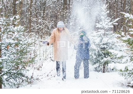 Fun and season concept - Happy mother and son having fun and playing with snow in winter forest Fun and season concept - Happy mother and son having fun and playing with snow in winter forest 71128626