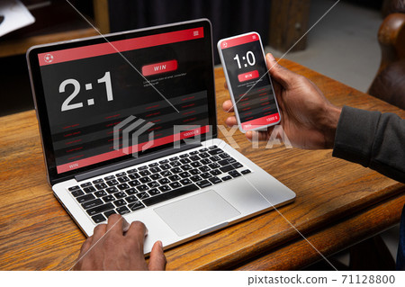 Close up laptop and smartphone screen with mobile app for betting and score 71128800