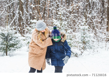 Portrait of happy mother with child son in winter outdoors. Snowy park. Single parent. Portrait of happy mother with child son in winter outdoors. Snowy park. Single parent. 71128816