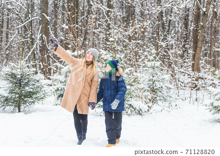 Portrait of happy mother with child son in winter outdoors. Snowy park. Single parent. Portrait of happy mother with child son in winter outdoors. Snowy park. Single parent. 71128820