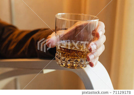 Man sitting on the chair and drinking whiskey. Man sitting on the chair and drinking whiskey. 71129178