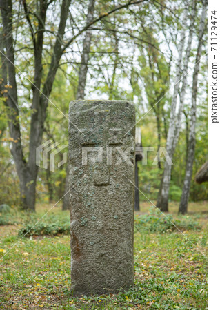 A worn sandstone grave marker in the shade on a very bright day. There is no text visible on the stone, but there is some moss on the top. Tombstone and graves in an ancient church graveyard. toned 71129474