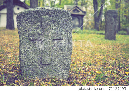 A worn sandstone grave marker in the shade on a very bright day. There is no text visible on the stone, but there is some moss on the top. Tombstone and graves in an ancient church graveyard. toned A worn sandstone grave marker in the shade on a very bright day. There is no text visible on the stone, but there is some moss on the top. Tombstone and graves in an ancient church graveyard. toned 71129495