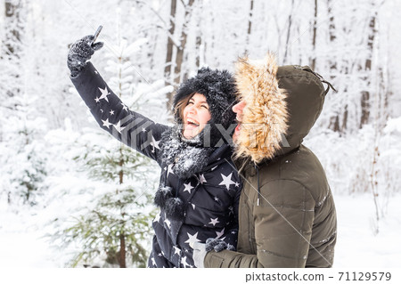 Season and relationship concept - Funny couple taking selfie in the winter time Season and relationship concept - Funny couple taking selfie in the winter time 71129579