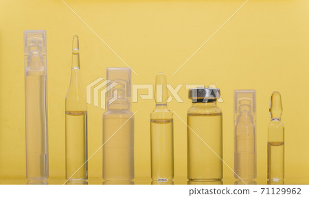 Glass medical ampoule vial for injection. Medicine is liquid sodium chloride with of aqueous solution in ampulla. Close up. Bottles ampule multicolor. 71129962