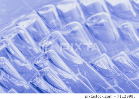 Glass medical ampoule vial for injection. Medicine is liquid sodium chloride with of aqueous solution in ampulla. Close up. Bottles ampule multicolor. 71129993