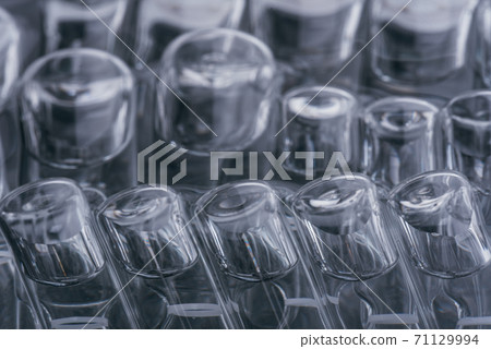 Glass medical ampoule vial for injection. Medicine is liquid sodium chloride with of aqueous solution in ampulla. Close up. Bottles ampule multicolor. 71129994