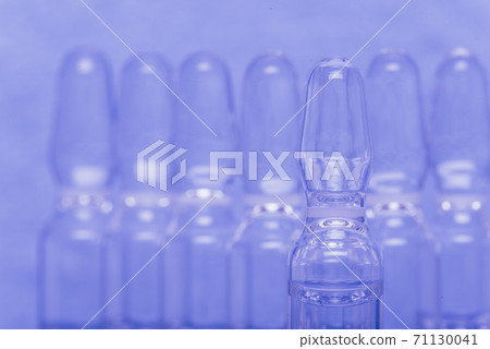 Glass medical ampoule vial for injection. Medicine is liquid sodium chloride with of aqueous solution in ampulla. Close up. Bottles ampule multicolor. 71130041